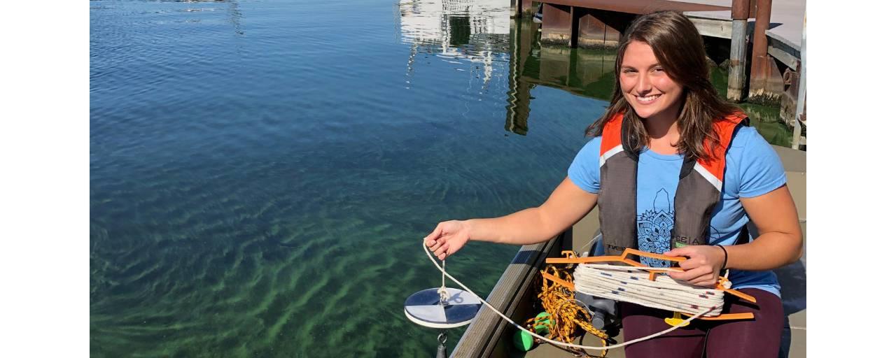 茉莉·曼库索在马斯基根湖蓝藻爆发时拿着一个塞奇圆盘